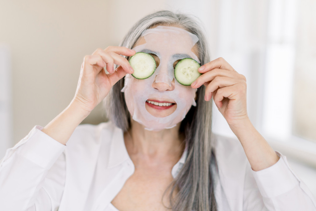 anti-aging mask on face skin, holding fresh cucumber slices